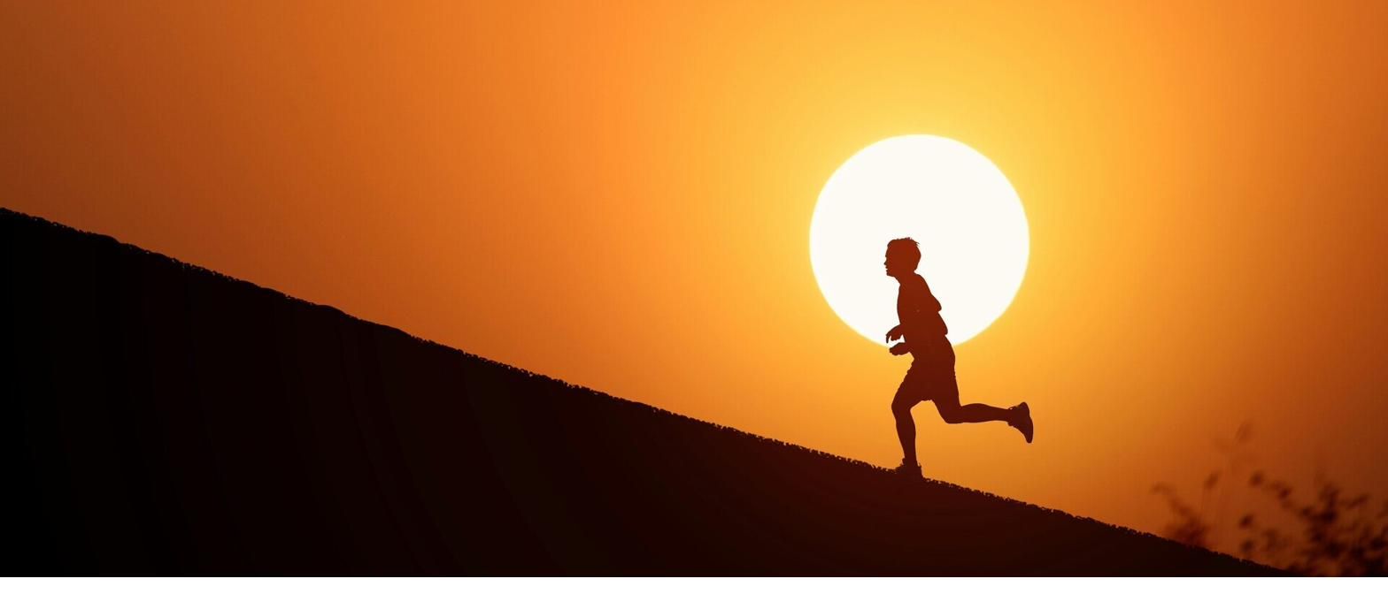 A runner alone in front of the setting sun