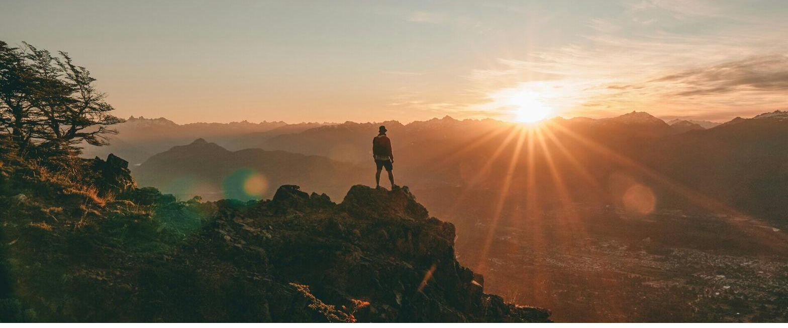 A hiker standing on a ridge at sunrise