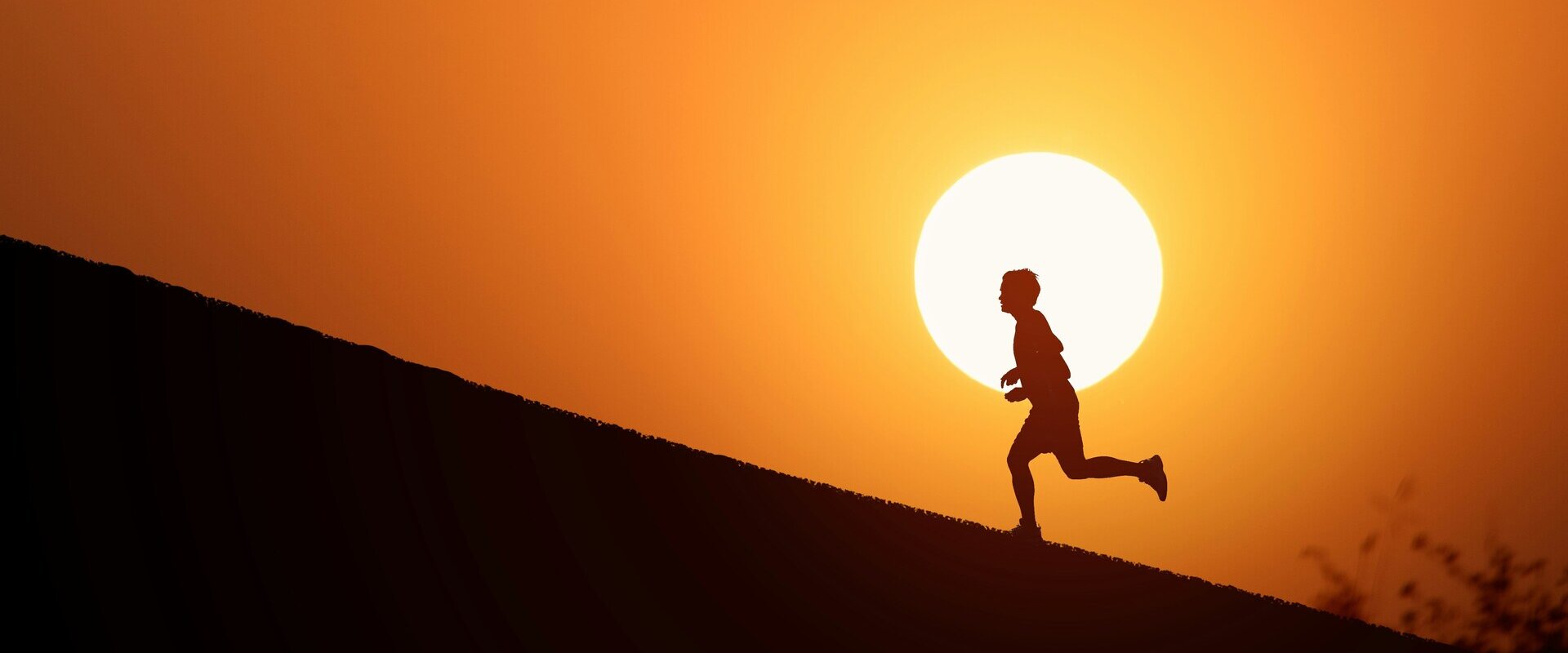 Ein Läufer allein vor einer riesigen untergehenden Sonne